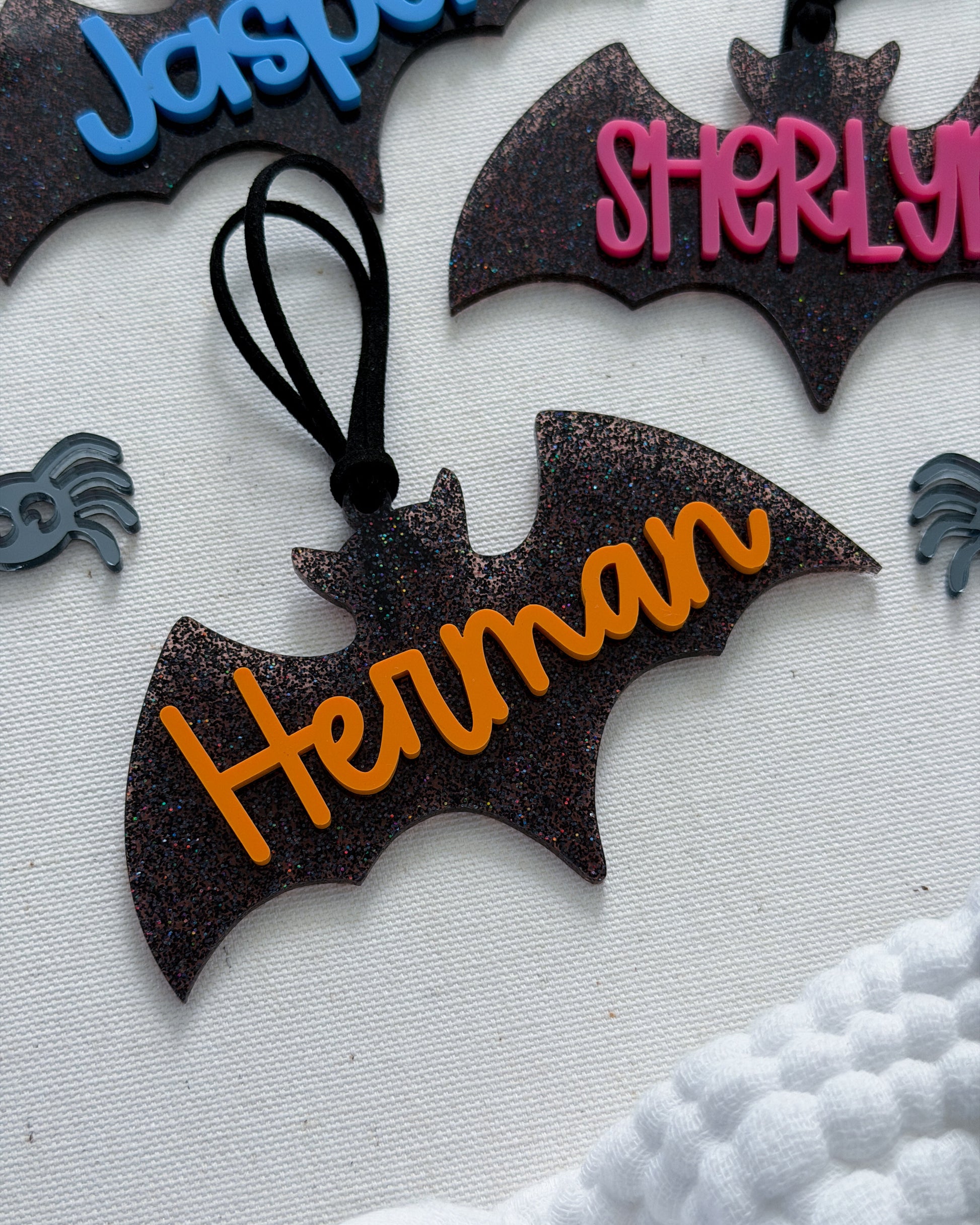 Bat-shaped decorations with personalized names in different colors on a textured surface.