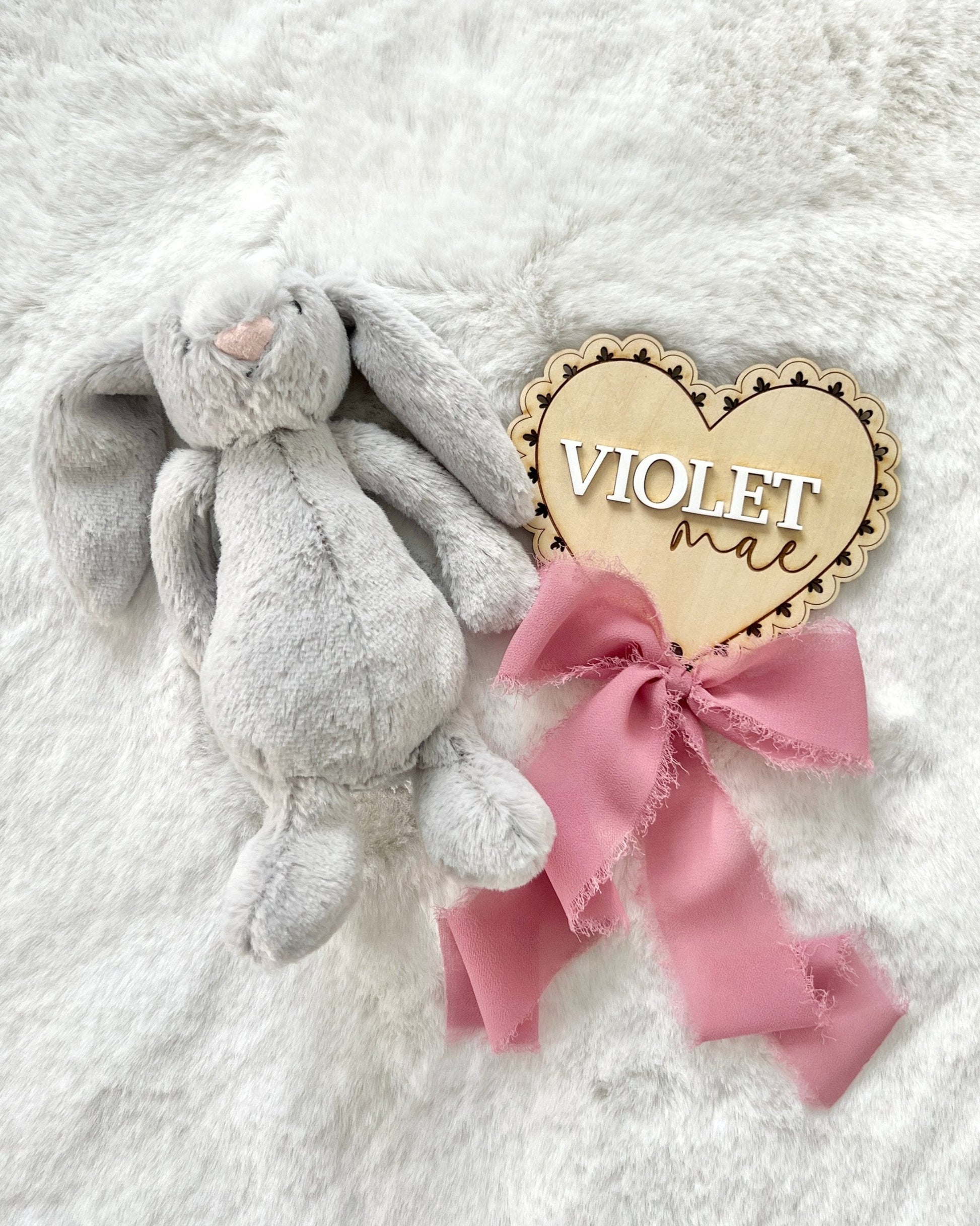 a personalized birch wood baby announcement name plaque that has a laser cut lace pattern and a chiffon bow.