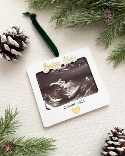 Decorative ornament with ultrasound photo and pine cones on a light background