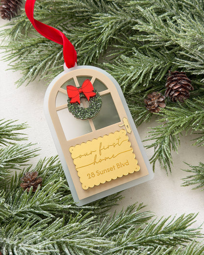 Decorative ornament with a red bow and wreath on a tag, surrounded by pine branches and cones.