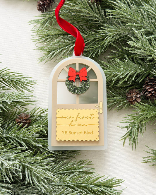 Decorative ornament with a wreath and text on a branch with pine cones