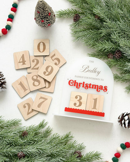 Wooden advent calendar with numbers, Christmas decorations, and a white box on a white background.