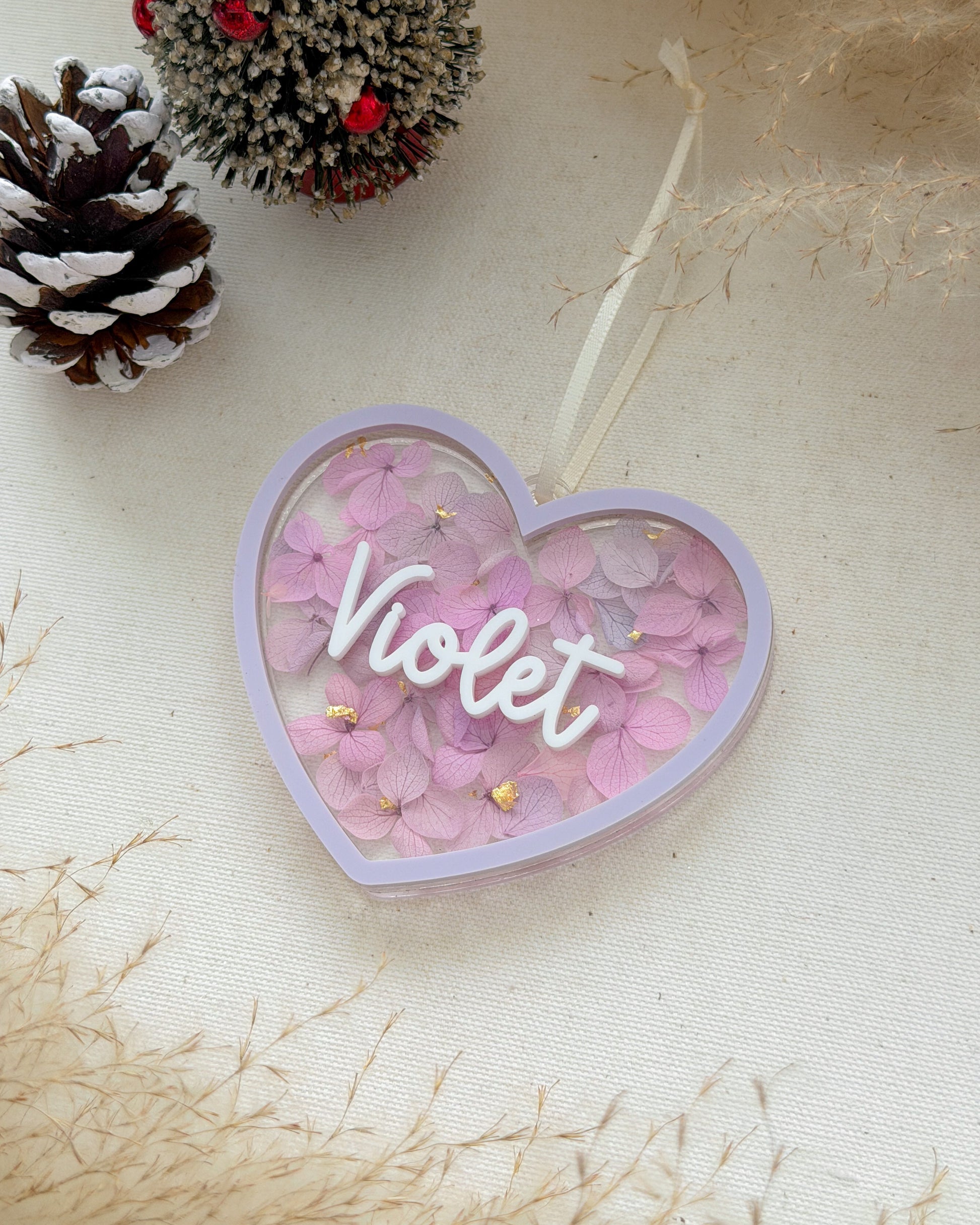 Heart-shaped decorative item with 'Violet' text on a light background with pinecones.