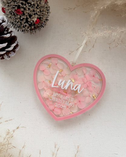 Heart-shaped ornament with 'Luna' and 'My First Christmas 2023' text, surrounded by decorative elements on a light background.
