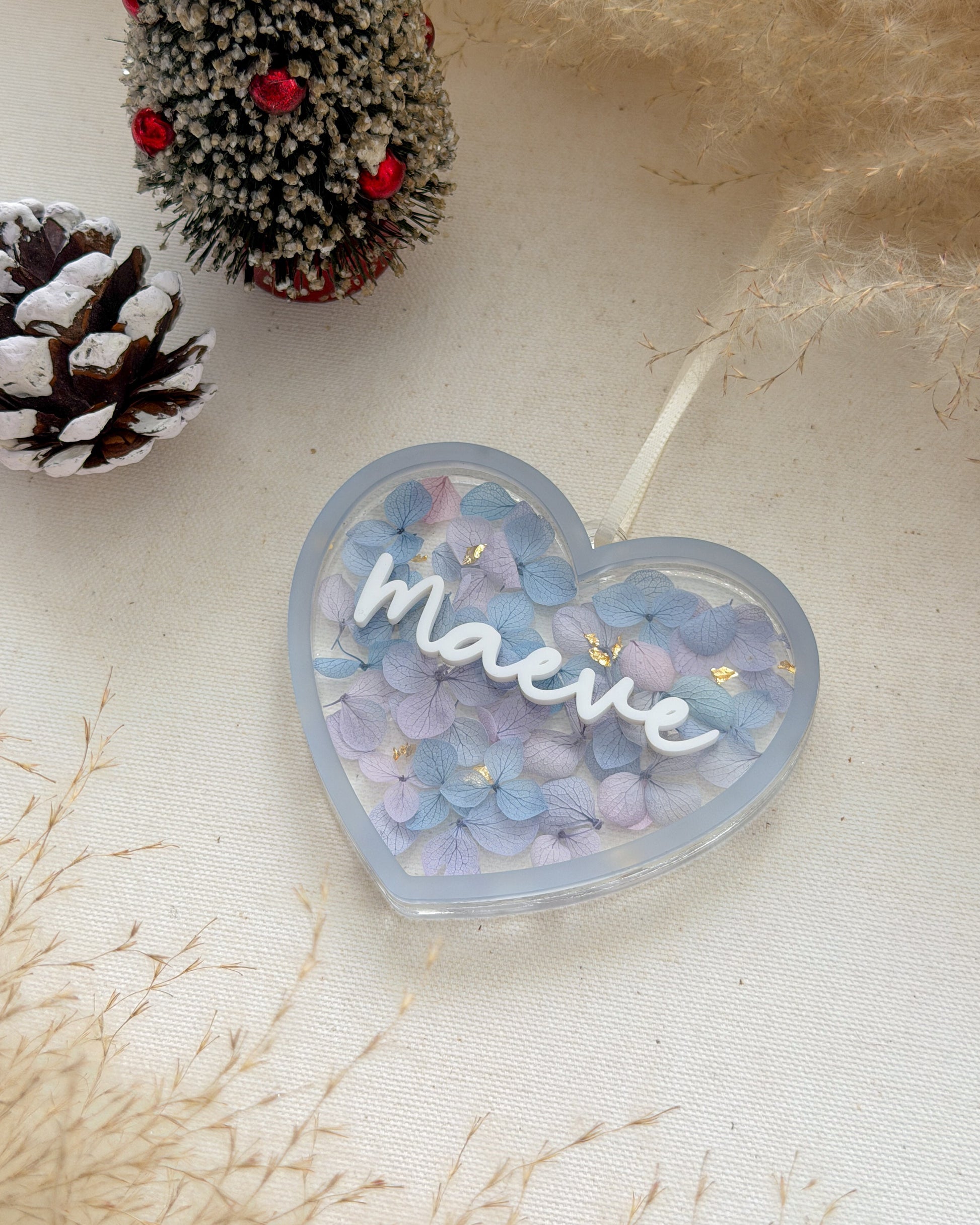 Heart-shaped container with 'Maeve' text, surrounded by decorative elements on a light background