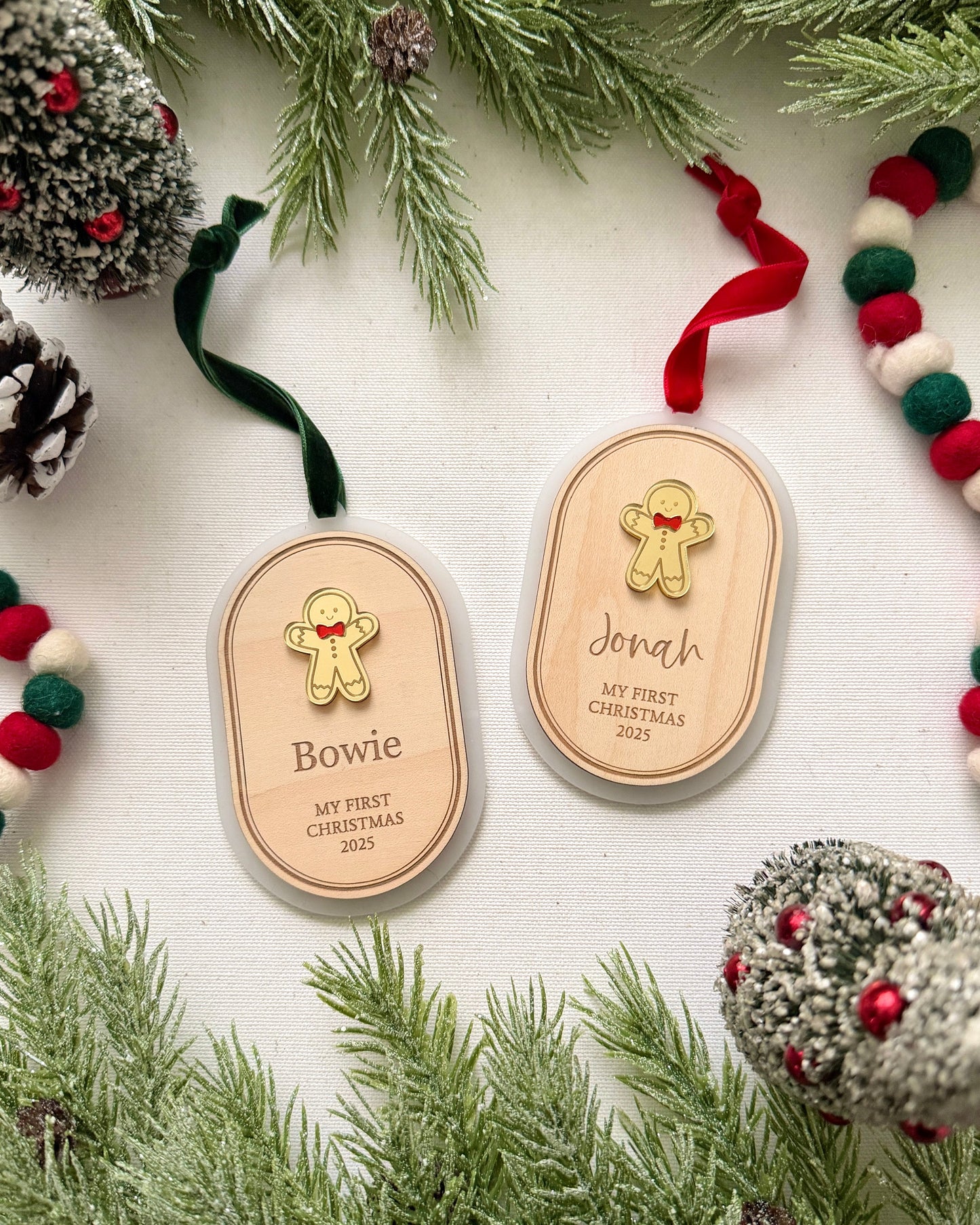 Two wooden ornaments with engraved names surrounded by Christmas decorations on a white background