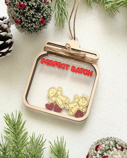 Decorative ornament with gingerbread men and red hearts on a white background with greenery.