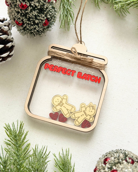 Decorative ornament with gingerbread men and red hearts on a white background with greenery.