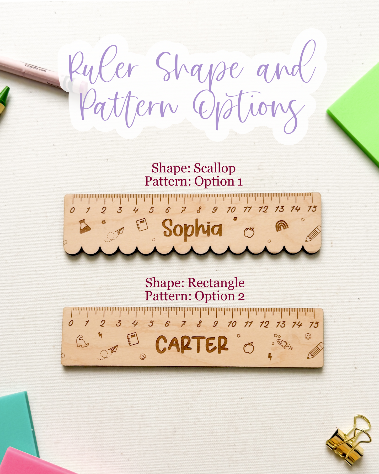 A styled flat-lay showing two wooden personalized rulers on a white surface with colorful paper clips, sticky notes, crayons, and a green paper corner. Text at the top reads 'Ruler Shape and Pattern Options,' with the top ruler labeled scalloped pattern option 1 and the bottom ruler labeled rectangular pattern option 2.