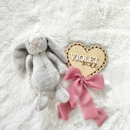 a personalized birch wood baby announcement name plaque that has a laser cut lace pattern and chiffon bow.