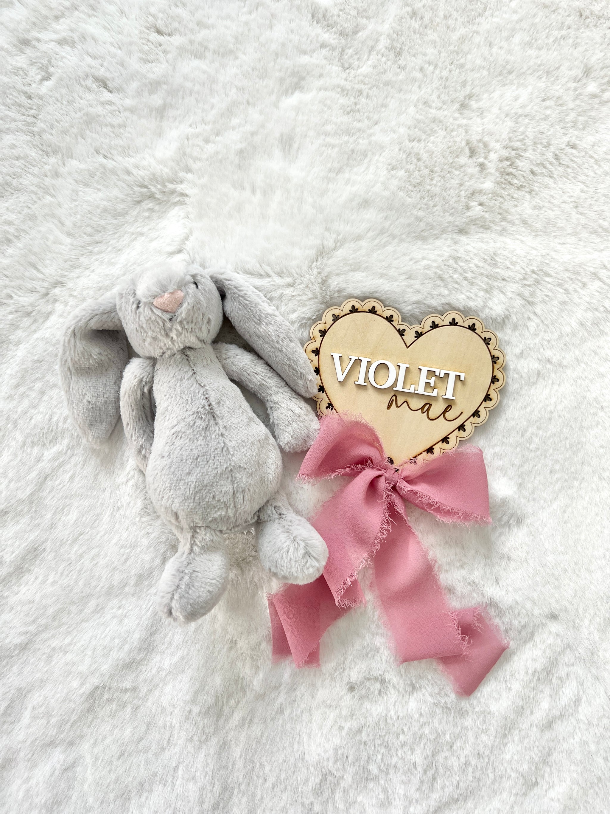 a personalized birch wood baby announcement name plaque that has a laser cut lace pattern and chiffon bow.